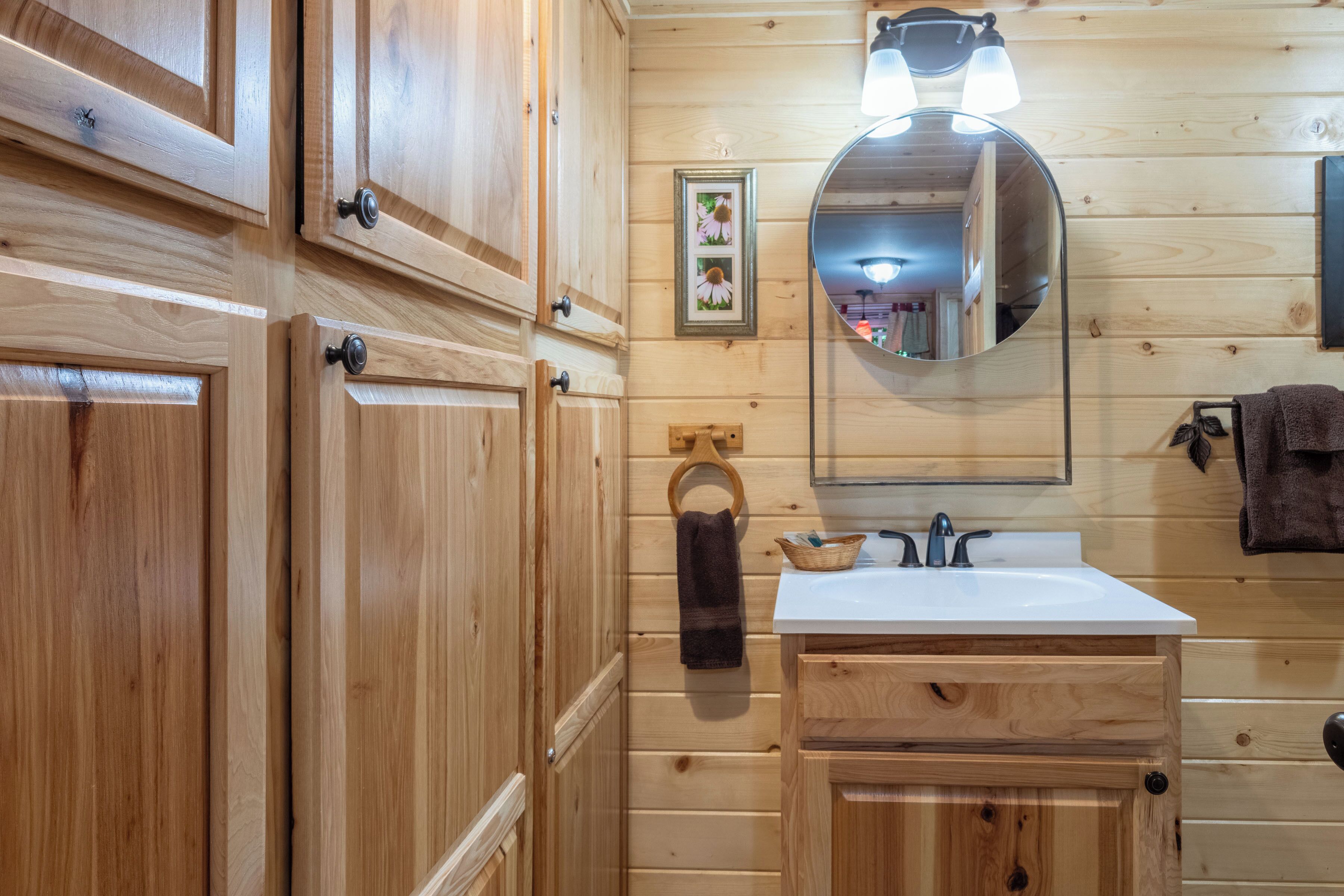 Een badkamer met houten lambrisering, een wastafel, spiegel en handdoekhouder.