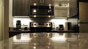 A kitchen with a stainless steel microwave, a coffee maker, and a toaster on a reflective countertop. - Heart of RVA Arts District Walk to VCU, MCV, The National, Quirk Prime Downtown (Richmond)