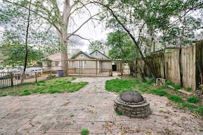 Enjoy a peaceful retreat in this serene backyard with a fire pit, wooden deck, and shaded patio.