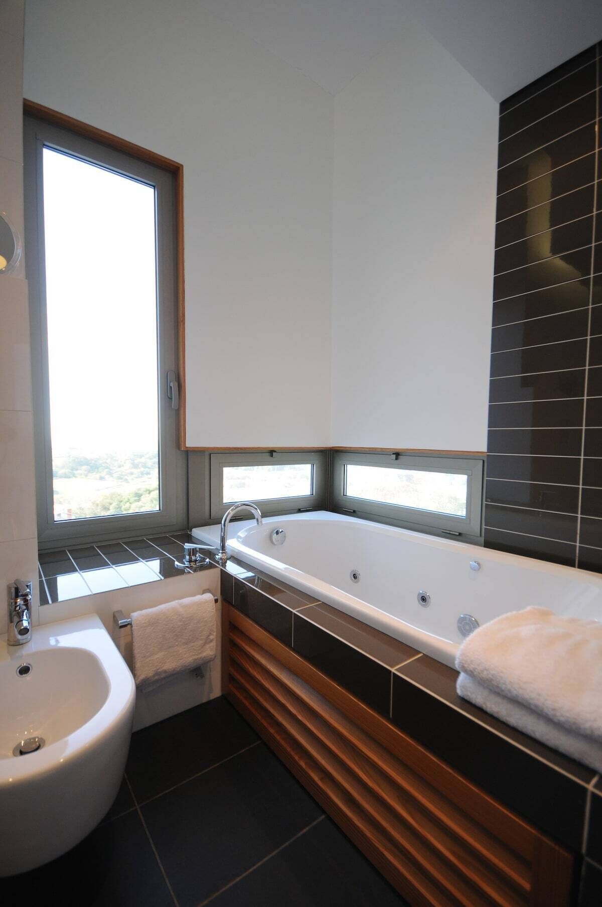 Une salle de bain moderne avec une baignoire, un lavabo et une fenêtre.