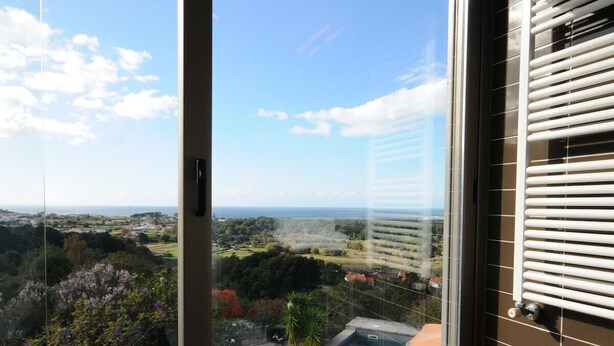 A balcony with a view of a swimming pool and surrounding landscape.