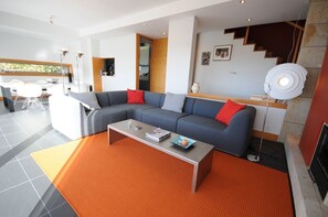 Una sala de estar moderna con un sofá seccional, una mesa de centro y un comedor con mesa y sillas.