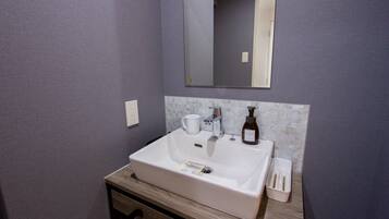A bathroom with a white sink, a mirror, and a tiled backsplash.