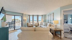 A spacious living room with a large sofa, a dining area, and a bedroom with a bed. - 3133 Villamare - Direct Oceanfront Views! (Hilton Head)