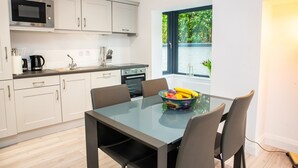 A modern kitchen with white cabinets, a microwave, and a dining area with a glass table and chairs. - New Modern Build on Muckross Road, Killarney, Kerry (Killarney)