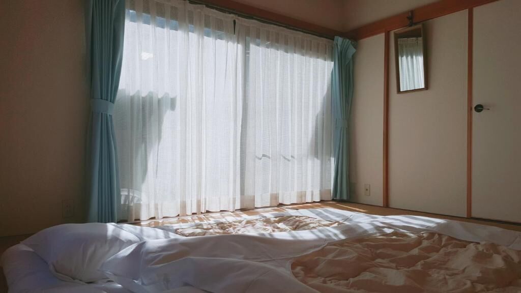 A bedroom with a bed, a wardrobe, and a window with curtains.