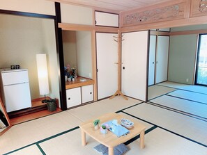 A traditional Japanese room with tatami flooring, a wooden table, a small sofa, and a cabinet with a mirror. - Yufuin Sunday (Yufu)