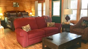 A cozy room with a red sofa, a wooden coffee table, and a patterned armchair.