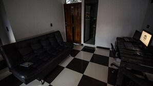 Une pièce avec un sol à carreaux noirs et blancs, un canapé en cuir noir et un bureau avec un ordinateur portable.