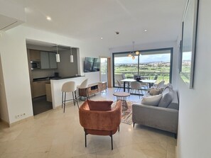 Enjoy a spacious living space with a kitchen, dining area, and sofa, offering a view of the surrounding green landscape.