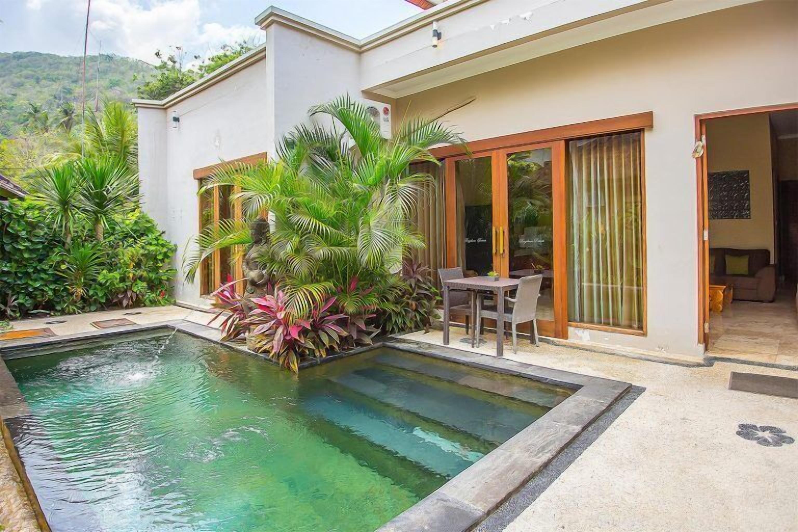 A modern house with a swimming pool, surrounded by lush greenery and a patio area.