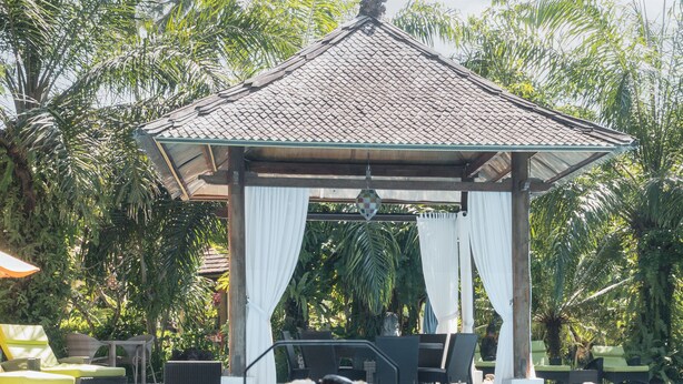 Área de piscina com um gazebo, cadeiras de descanso e uma bandeja com doces e um bule de chá.
