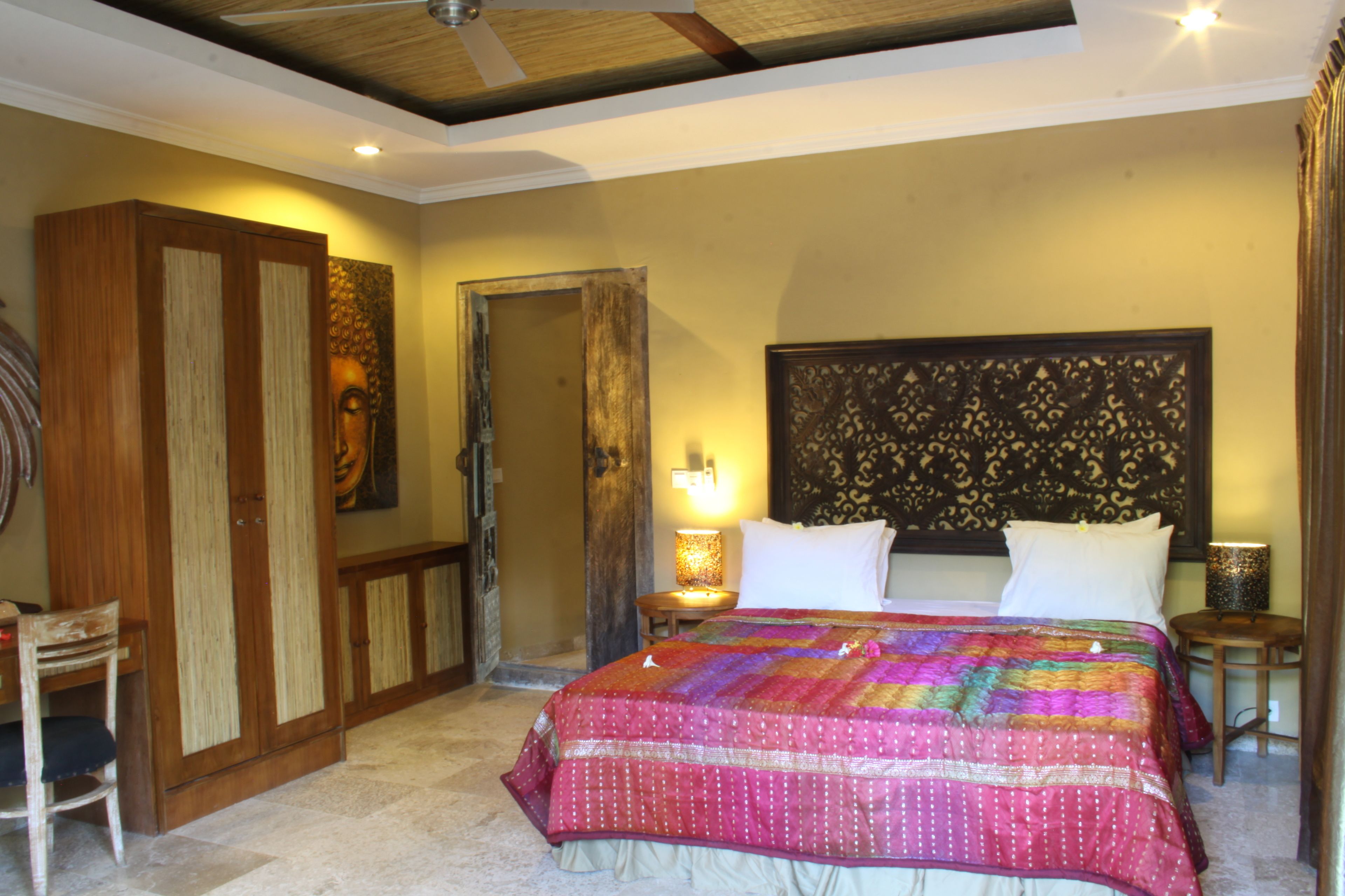Quarto com cama grande, guarda-roupa de madeira e mesa de cabeceira com abajur.