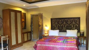 Quarto com cama grande, guarda-roupa de madeira e mesa de cabeceira com abajur.