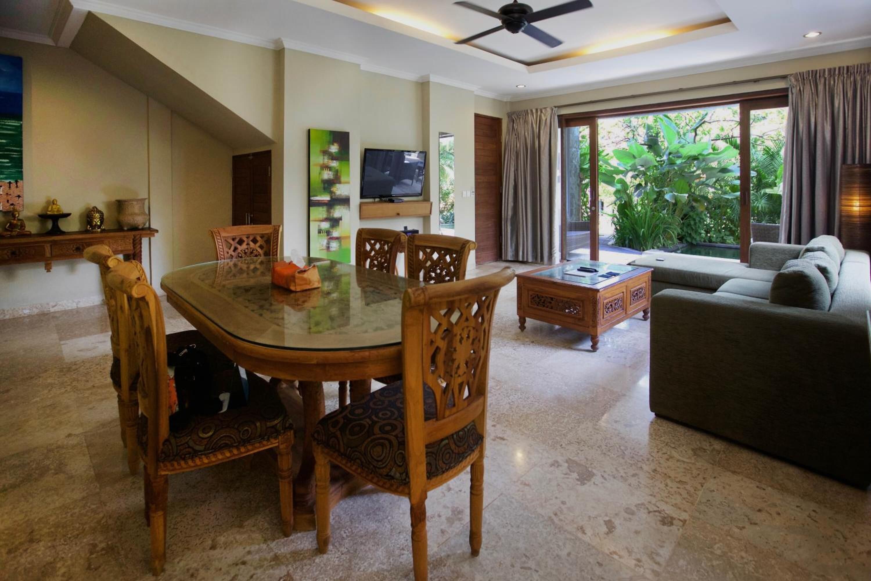 A spacious living area with a dining table, chairs, a sofa, and a TV.