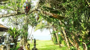 Um jardim com estátuas, um caminho e vista para o oceano.