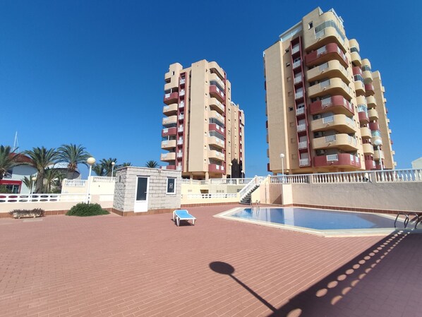 A pool area with two high-rise buildings in the background. - 6th floor, front line facing the Mediterranean (La Manga del Mar Menor)