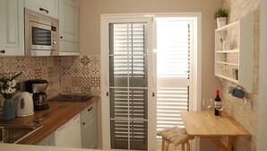 A compact kitchen with a built-in oven, a coffee maker, and a small dining table with two wine glasses and a bottle. - The best solution for couples in love (Maspalomas)