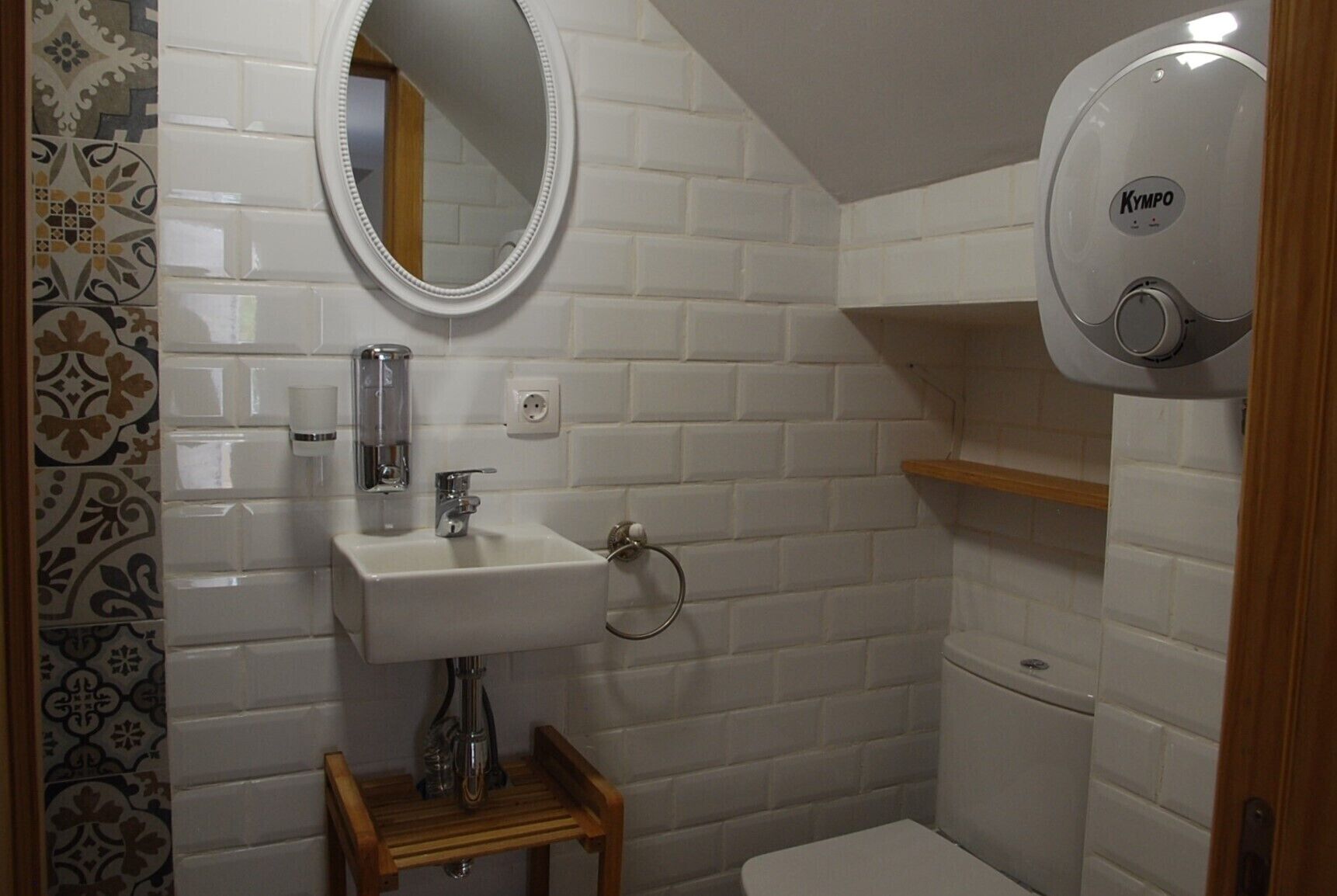 A bathroom with a white sink, mirror, and a hand dryer.