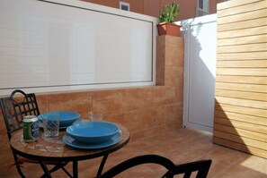 A patio with a tiled table, blue plates, a glass, and a can of beer.