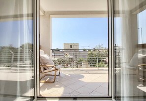 Un balcon donnant sur le paysage urbain, une chaise et une petite table.