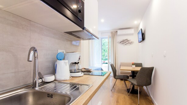 Una cocina moderna con un lavamanos de acero inoxidable, una cafetera y un comedor con mesa y sillas.