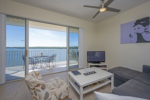 Relax in this stylish living room with a balcony offering a stunning water view, a comfortable sofa, and a flat-screen TV.