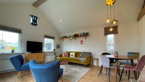 A living room with a sofa, chairs, a TV, and a dining area. - Modern chalet situated on the edge of the park. This chalet has much to offer for both adults and ch (Burgh-Haamstede)