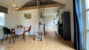 A modern kitchen with a wooden staircase, a dining area with chairs, and a view of the kitchen through a door. - Modern chalet situated on the edge of the park. This chalet has much to offer for both adults and ch (Burgh-Haamstede)