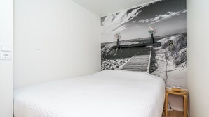 A bedroom with a bed, a nightstand, a wall-mounted shelf, and a power outlet. - Modern chalet situated on the edge of the park. This chalet has much to offer for both adults and ch (Burgh-Haamstede)
