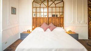 A large bed with a wooden headboard, two nightstands, and a framed picture on the wall. - Meson del Carmen (Puebla)