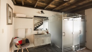 A bathroom with a concrete sink, a glass shower enclosure, and a wooden chair. - Meson del Carmen (Puebla)