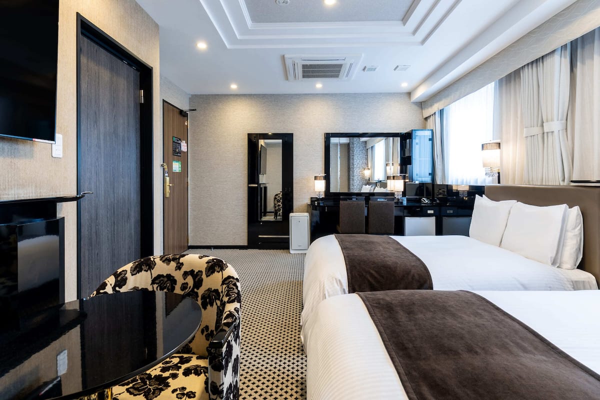Ein Hotelzimmer mit einem großen Bett, einem Schreibtisch mit Stuhl, einem Fernseher und einem Spiegel.