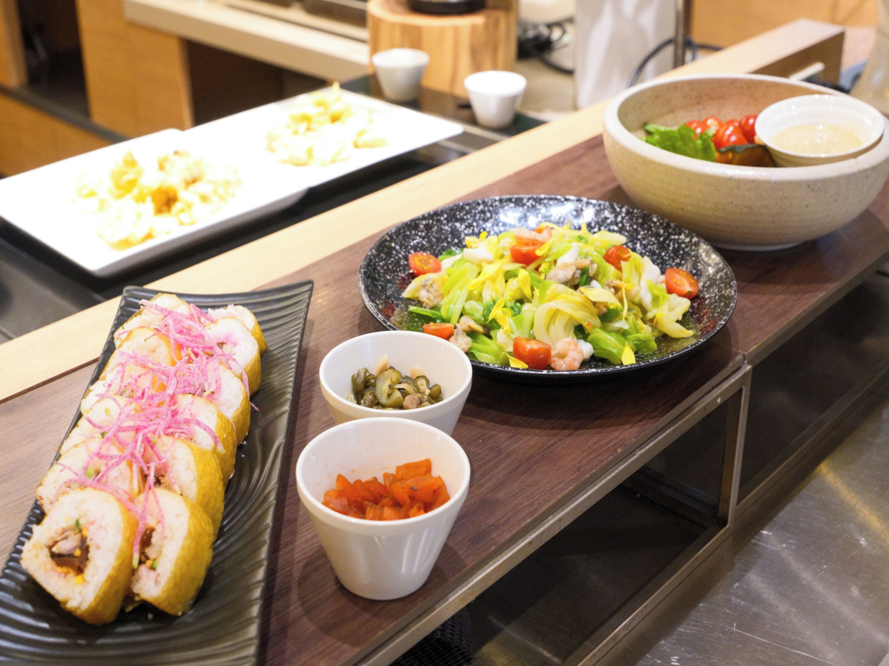 A dining table with various dishes, including sushi, a salad, and small bowls of condiments.
