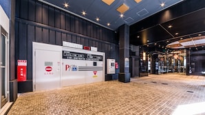 Entrada de hotel con suelo de ladrillo, un indicador digital de estacionamiento y un extintor.