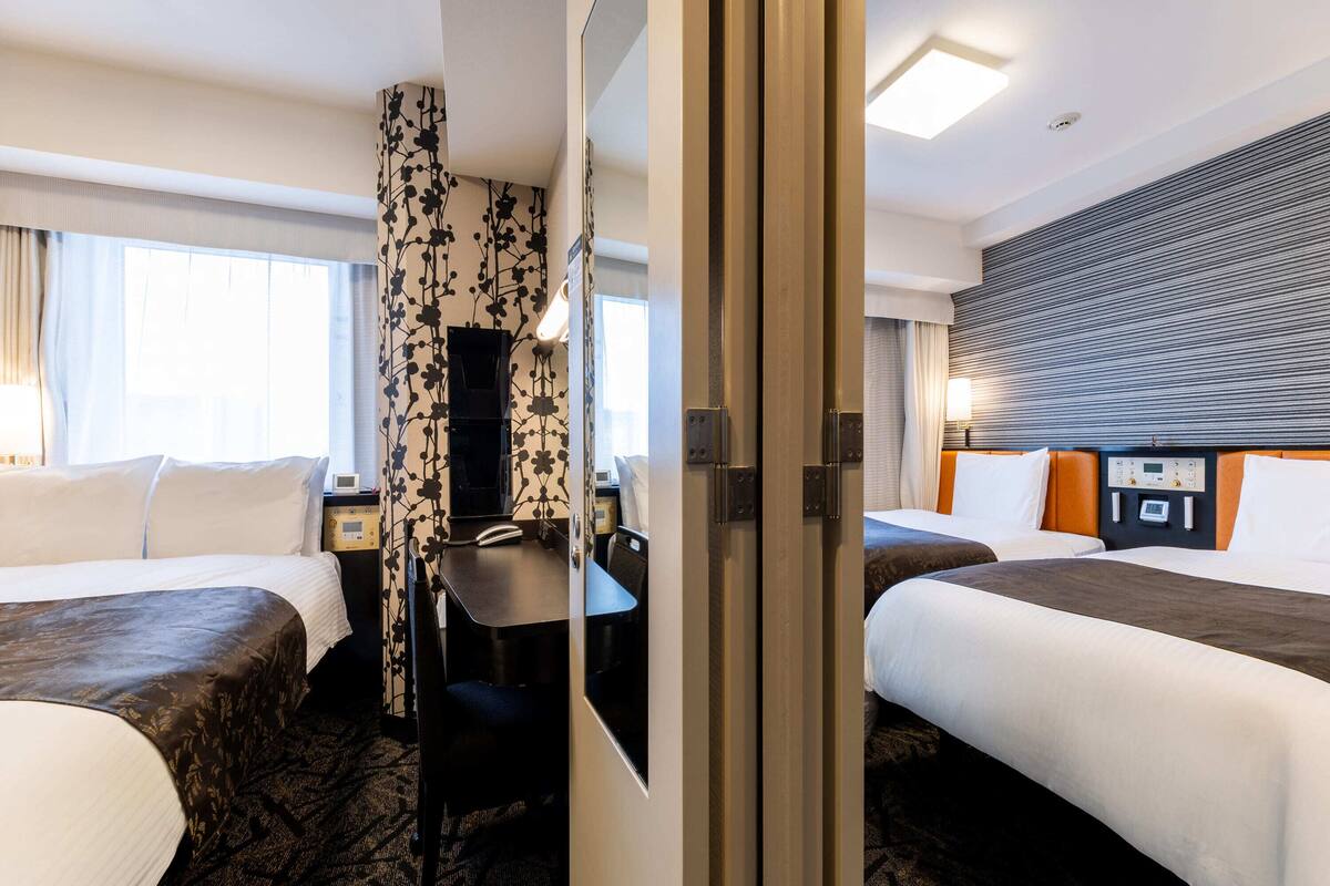Ein Hotelzimmer mit zwei Betten, einem Schreibtisch und einer Duschkabine.