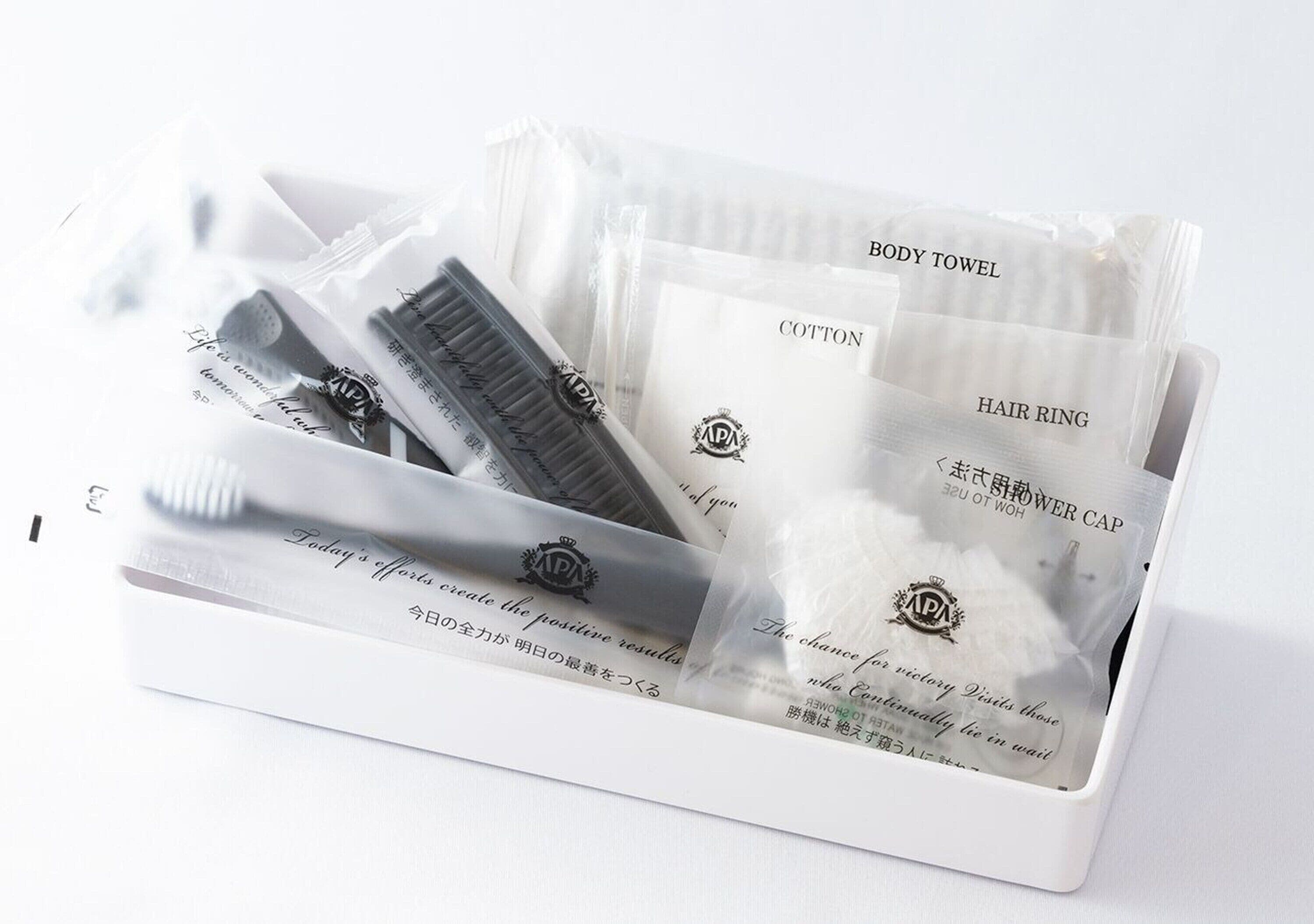 A white box containing a body towel, hair ring, and a shower cap.