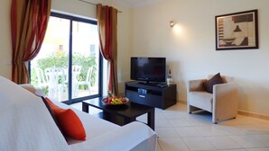 A modern living room with a sofa, a TV, and a dining table with fruit. - 2 Bed House, Pera,  Nr. Albufeira, Algarve. - Shared Pool (PERA)
