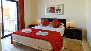 A hotel bedroom with a bed, two bedside tables, a nightstand, a window with curtains, and a painting on the wall. - 2 Bed House, Pera,  Nr. Albufeira, Algarve. - Shared Pool (PERA)