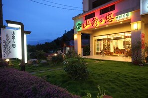 Un restaurant amb un cartell ben il·luminat i un jardí ben cuidat al davant.