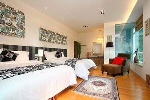 Two single beds, a comfortable armchair, and a large window offer a serene view of the outside.