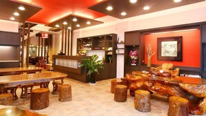 Un vestíbulo moderno con mostrador de recepción, zona de estar y una mesa de madera decorativa.