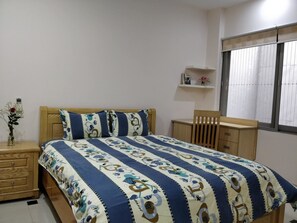 A bedroom with a bed, wooden nightstand, and a chair.