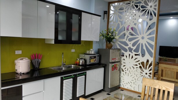 Cozinha moderna com armários brancos, bancada preta e divisória decorativa.