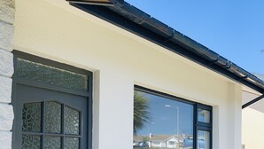 Un edificio con facciata in pietra, una porta nera con pannelli di vetro e una finestra che si affaccia sulla strada.