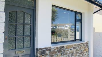 A building with a stone facade, a black door with glass panels, and a window with a view of the street.