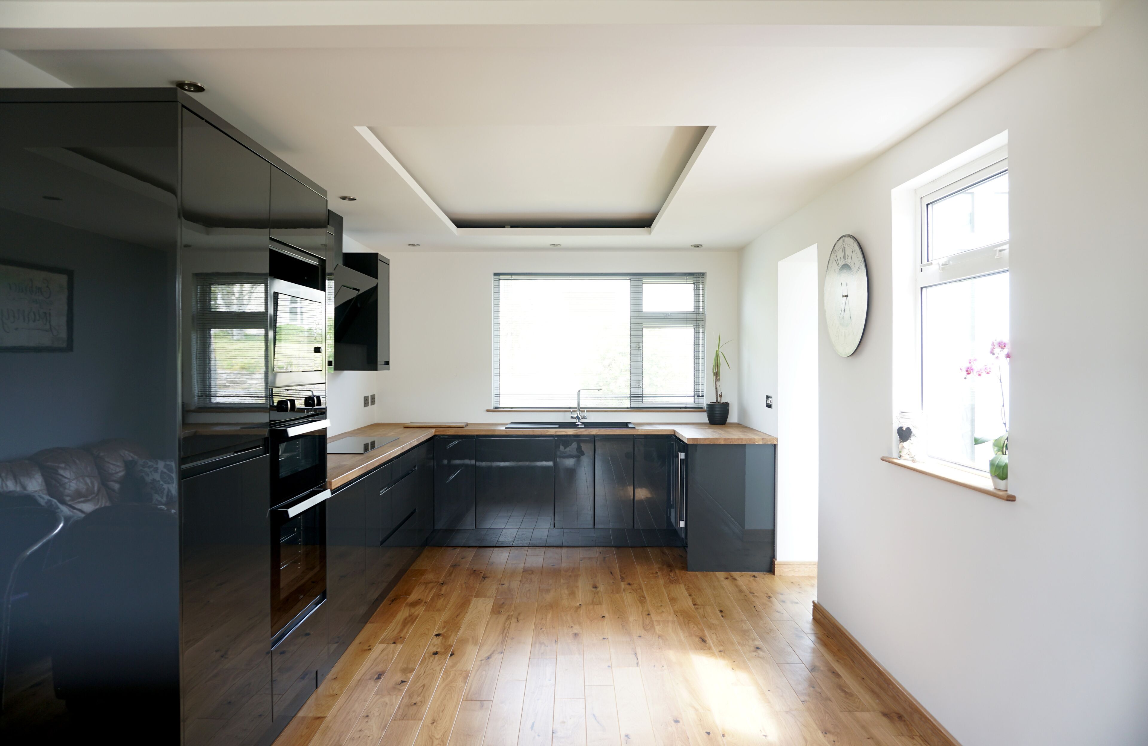 A modern kitchen with a large window, built-in appliances, and wooden flooring.