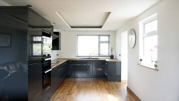 A modern kitchen with a large window, built-in appliances, and wooden flooring.