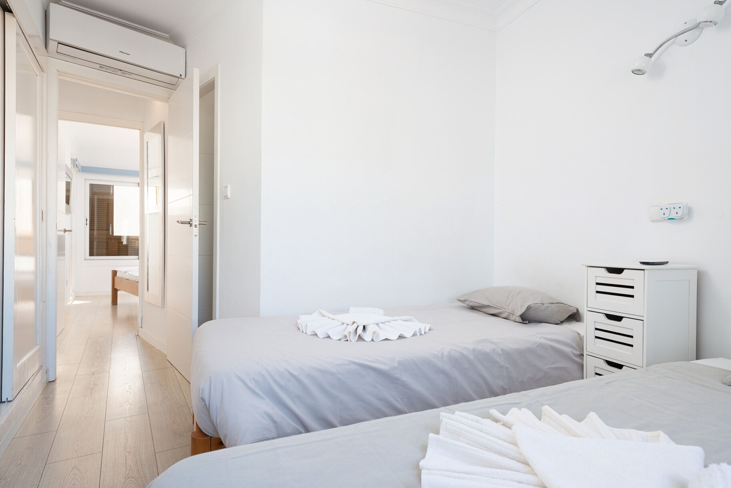 Ein modernes Hotelzimmer mit zwei Betten, einem begehbaren Kleiderschrank und einer Dusche.