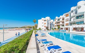 A resort with a pool, sun loungers, and a beach area.
